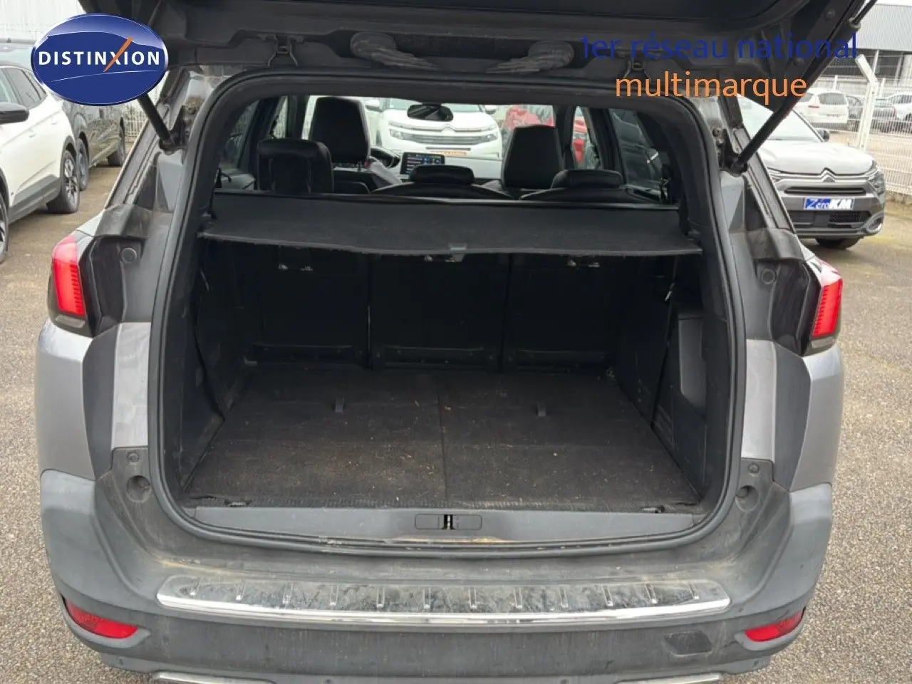 Coffre ouvert d’un Peugeot 5008 gris Artense vu de l’arrière, montrant l’espace de chargement et la plage arrière.