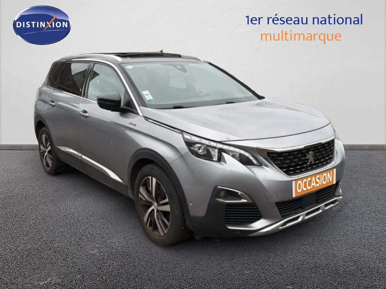 Peugeot 5008 gris Artense en 3/4 avant droit, SUV 5 portes avec jantes alliage et calandre noire distinctive.
