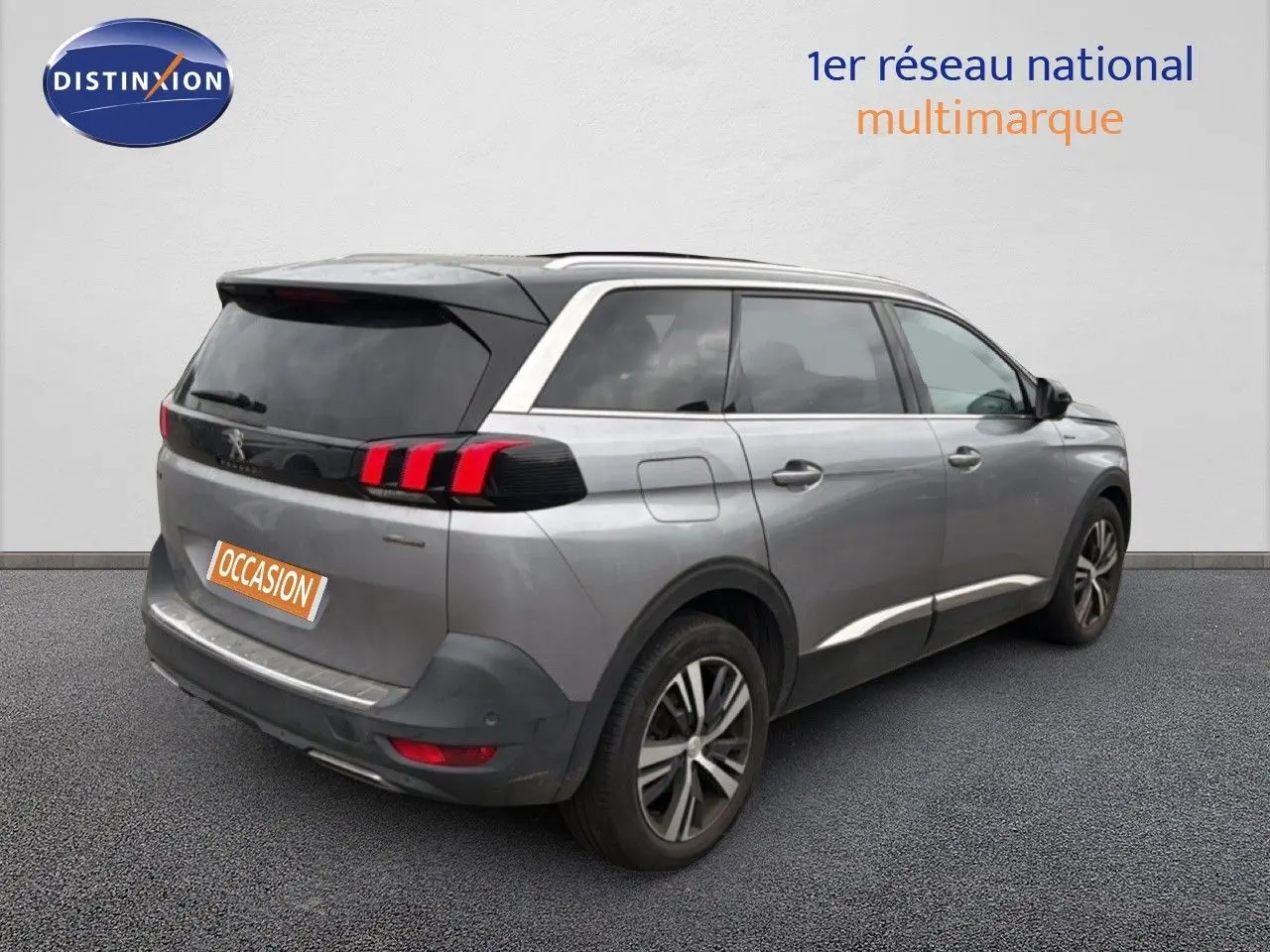 Vue 3/4 arrière droite d’un Peugeot 5008 gris Artense avec feux arrière à griffes rouges et jantes alliage bicolores.
