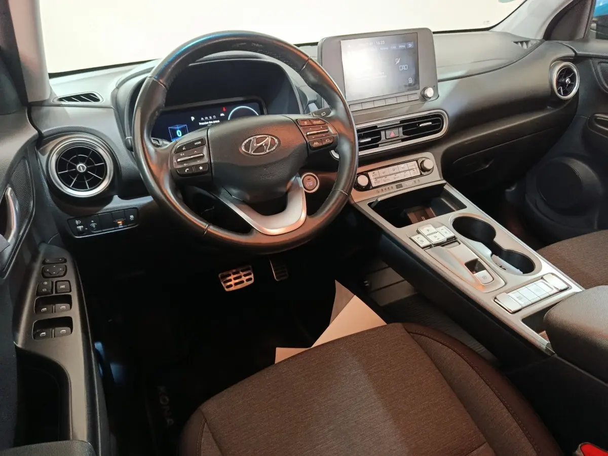 Vue intérieure côté conducteur du tableau de bord et console centrale du Hyundai Kona électrique 2022 avec écran tactile et volant cuir.