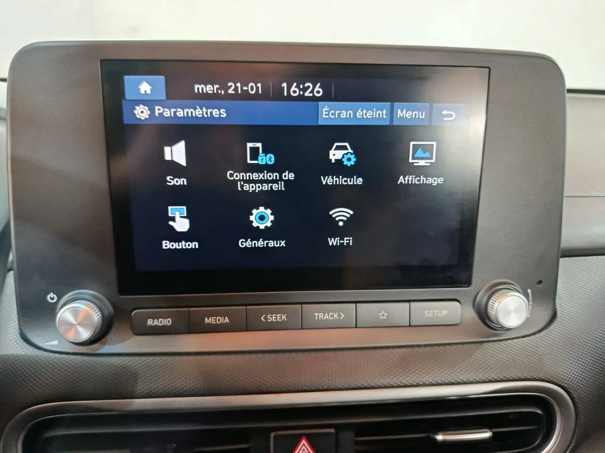 Écran tactile central allumé affichant les paramètres multimédia dans l'habitacle du Hyundai Kona bleu.