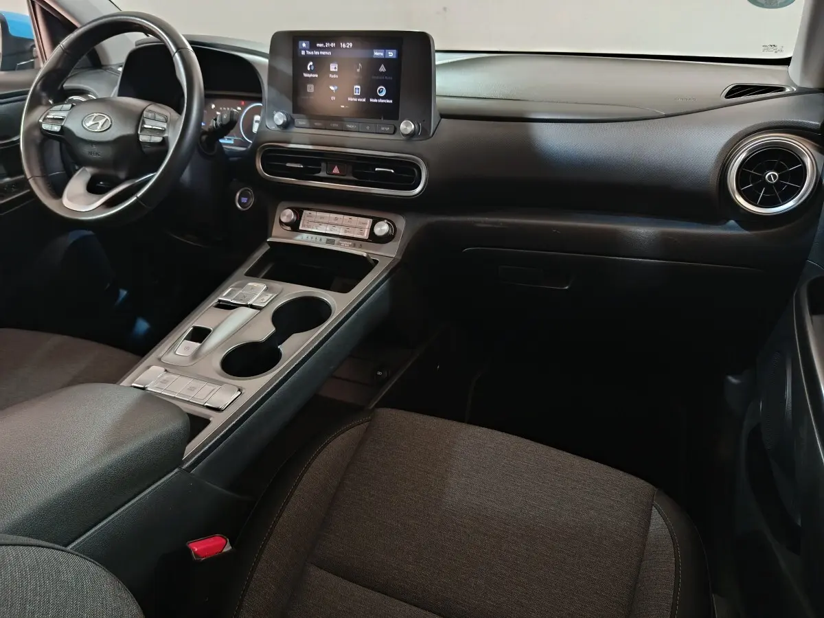 Vue intérieure du tableau de bord et console centrale de la Hyundai Kona électrique 2022 avec écran tactile et volant multifonction noir.
