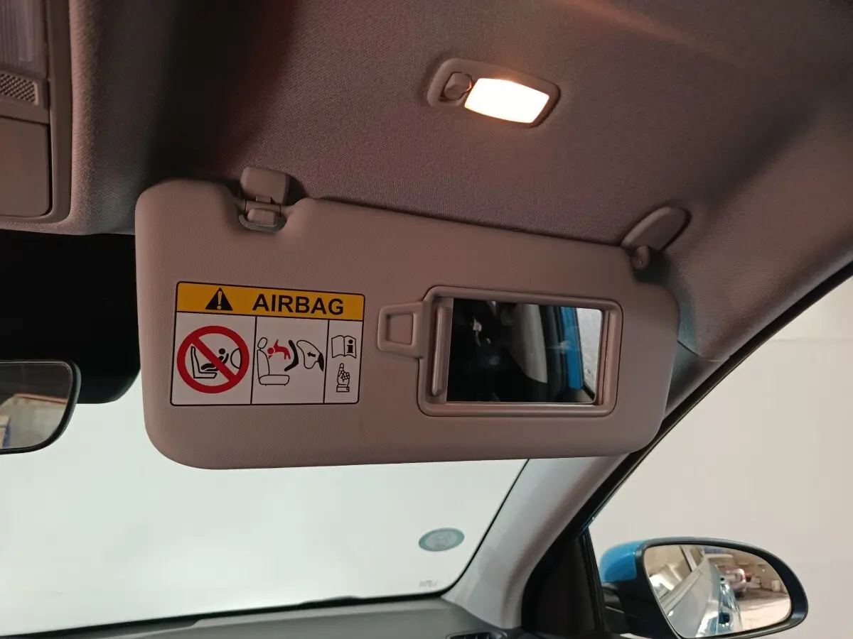Détail du pare-soleil côté conducteur avec miroir et avertissement airbag, intérieur du Hyundai Kona bleu visible au rétroviseur.