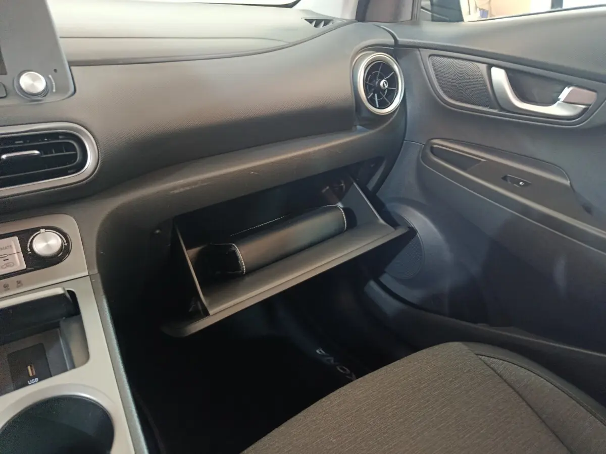 Intérieur côté passager du Hyundai Kona électrique 2022, boîte à gants ouverte avec pochette noire visible.