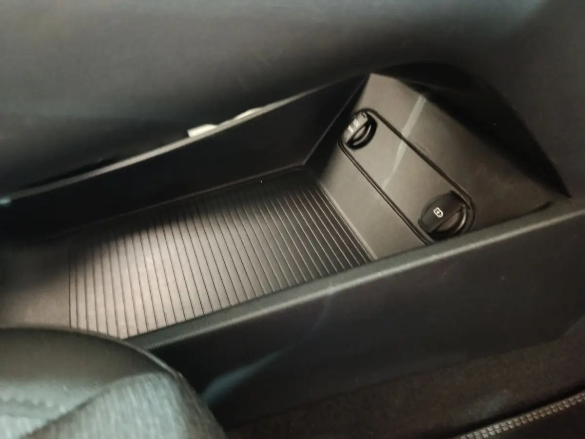 Gros plan sur le rangement central noir avec commandes des vitres dans l’habitacle du Hyundai Kona électrique bleu.