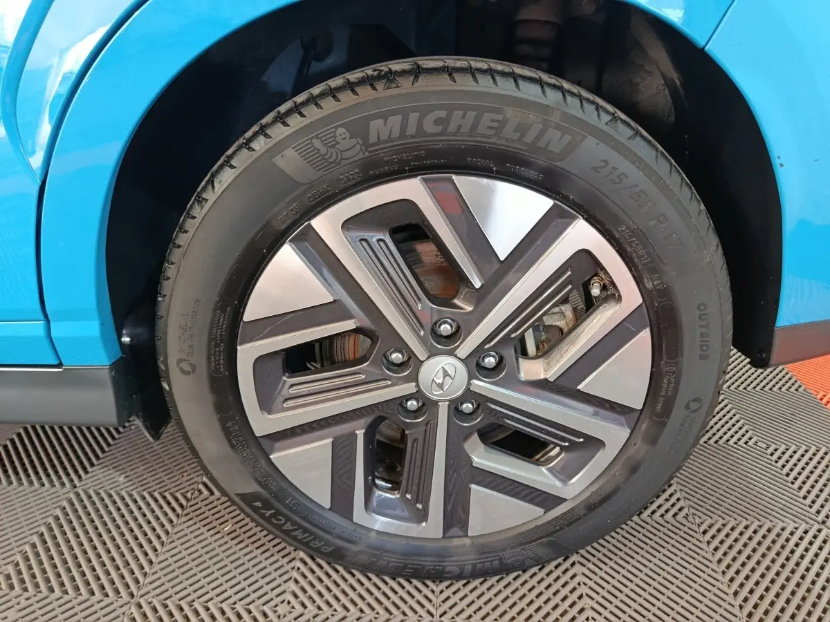 Gros plan sur la roue avant gauche d’une Hyundai Kona électrique bleue, avec jante alliage et pneu Michelin.