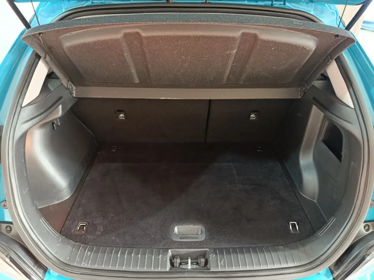 Coffre ouvert vu de l'arrière d'une Hyundai Kona électrique bleu 2022, espace de chargement vide et propre.