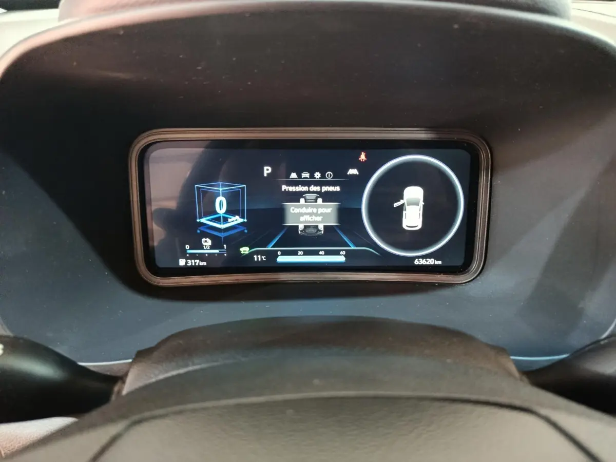 Vue rapprochée du tableau de bord numérique du Hyundai Kona électrique 2022, affichant la pression des pneus et l'autonomie.