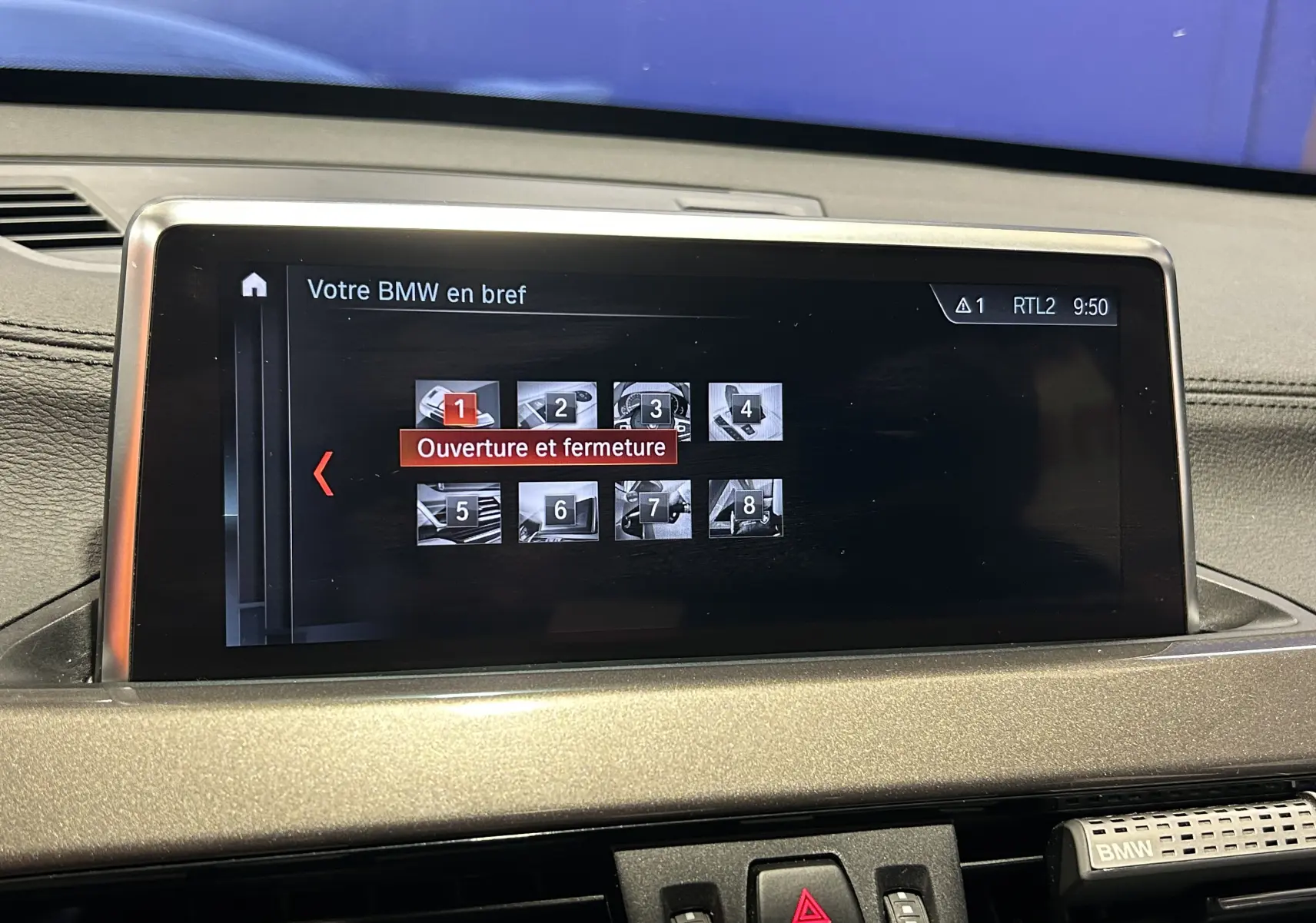 Écran central du tableau de bord d'une BMW X1 gris, affichant le menu "Ouverture et fermeture" en intérieur.