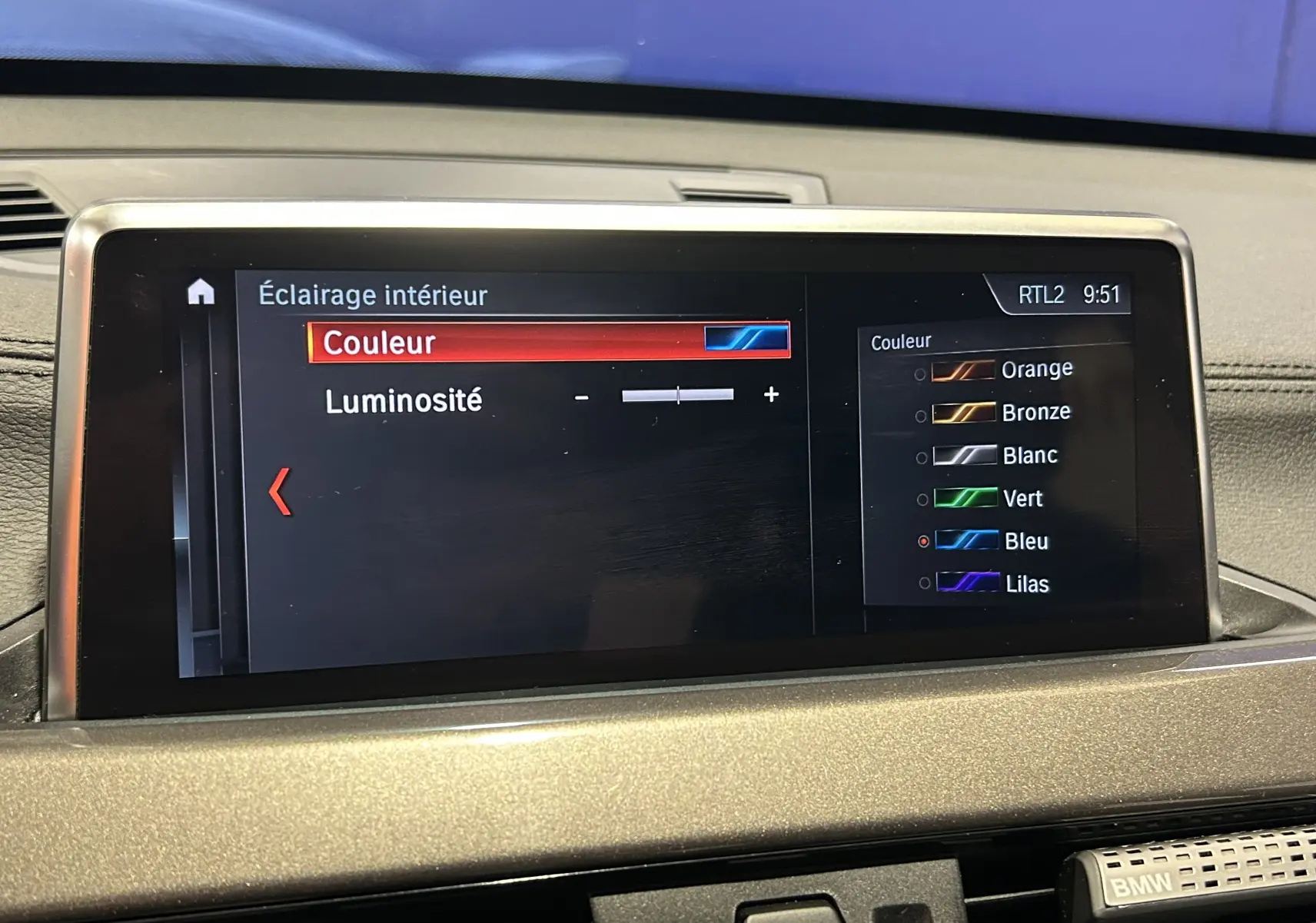 Écran central de BMW X1 gris montrant le réglage de l’éclairage intérieur avec choix de couleur en mode bleu.