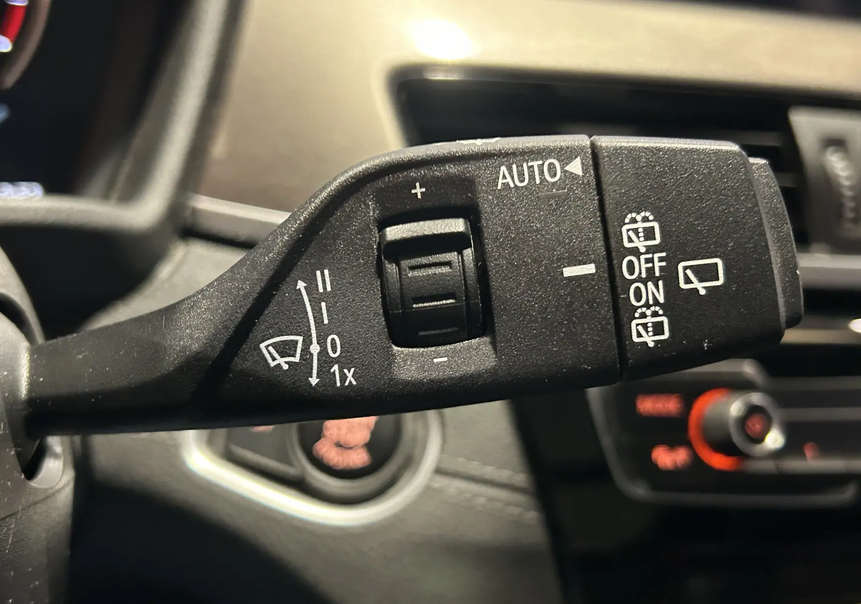 Gros plan sur la commande des essuie-glaces à gauche du volant dans l’habitacle d’un BMW X1 gris de 2021.