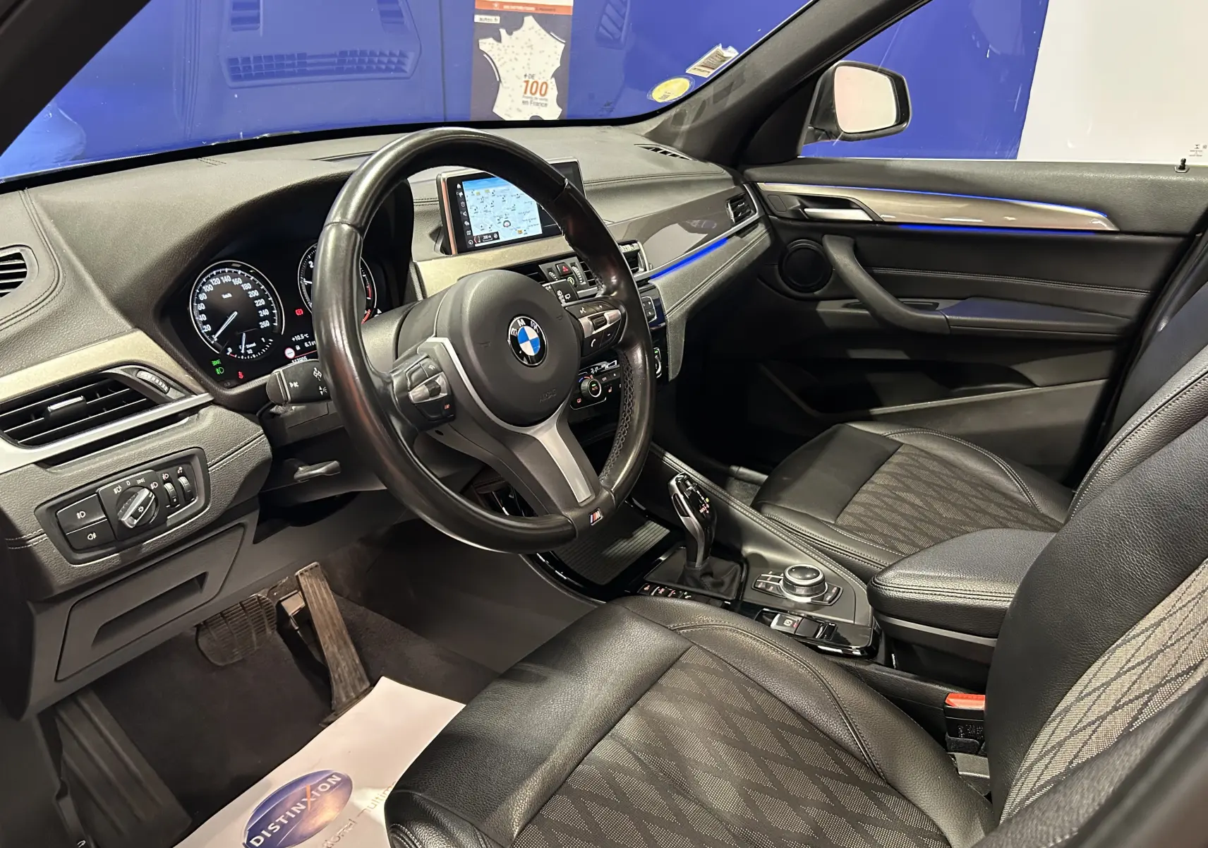 Intérieur noir de BMW X1 2021 vu côté conducteur, avec tableau de bord digital et console centrale moderne.