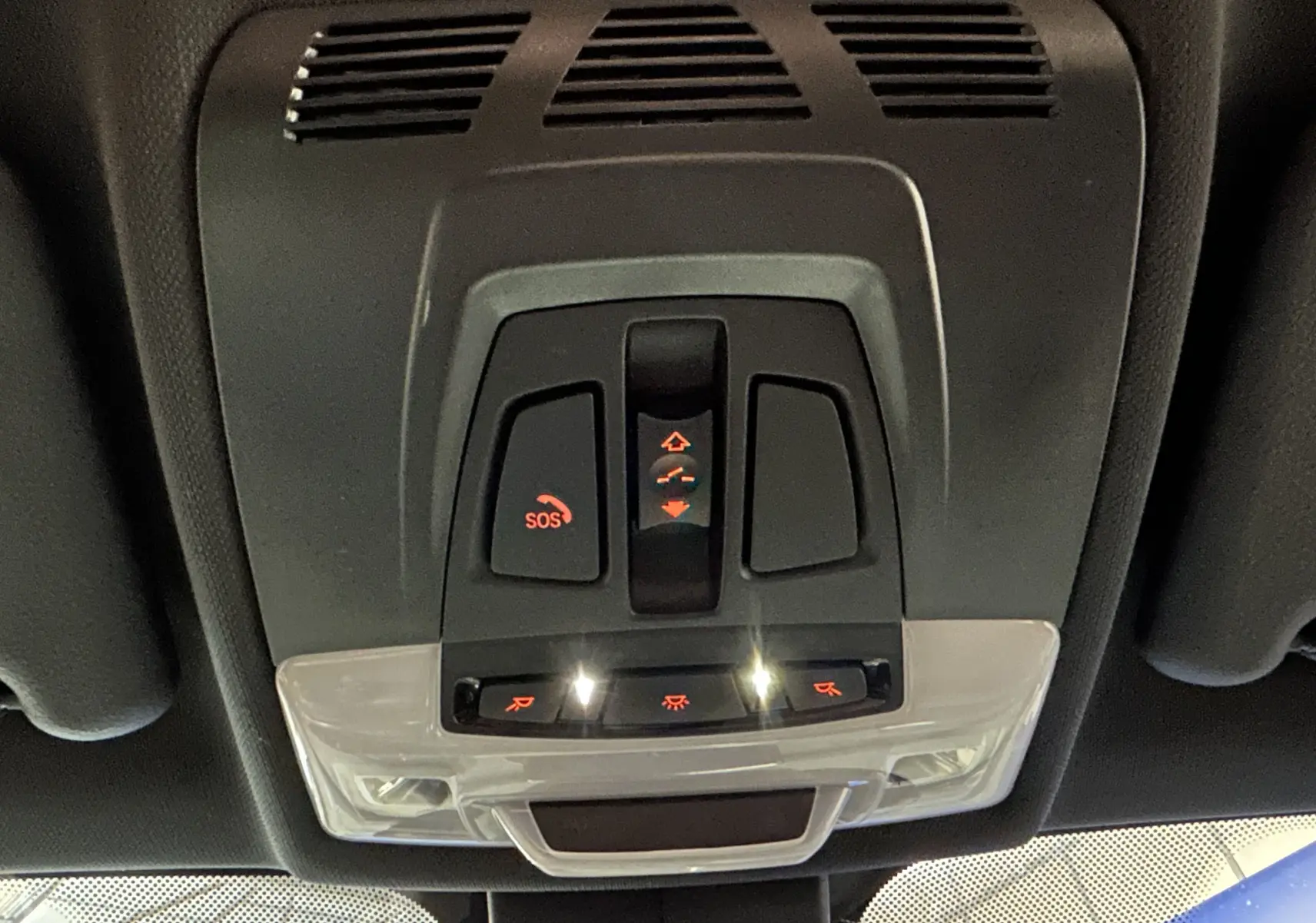 Vue en contre-plongée du panneau de commandes du toit ouvrant et éclairage intérieur du BMW X1 gris 2021.