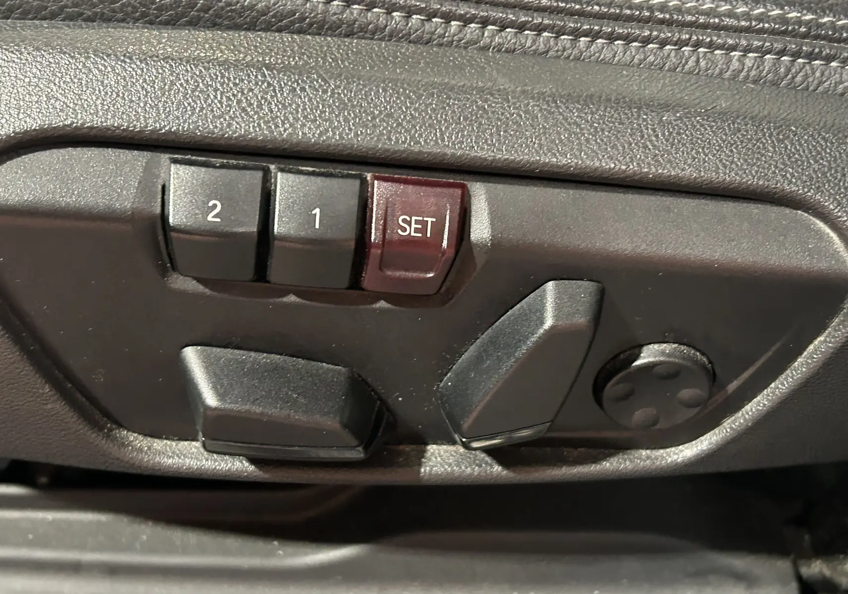 Boutons de réglage électrique des sièges avec mémorisation sur le côté gauche d'un BMW X1 gris 2021.