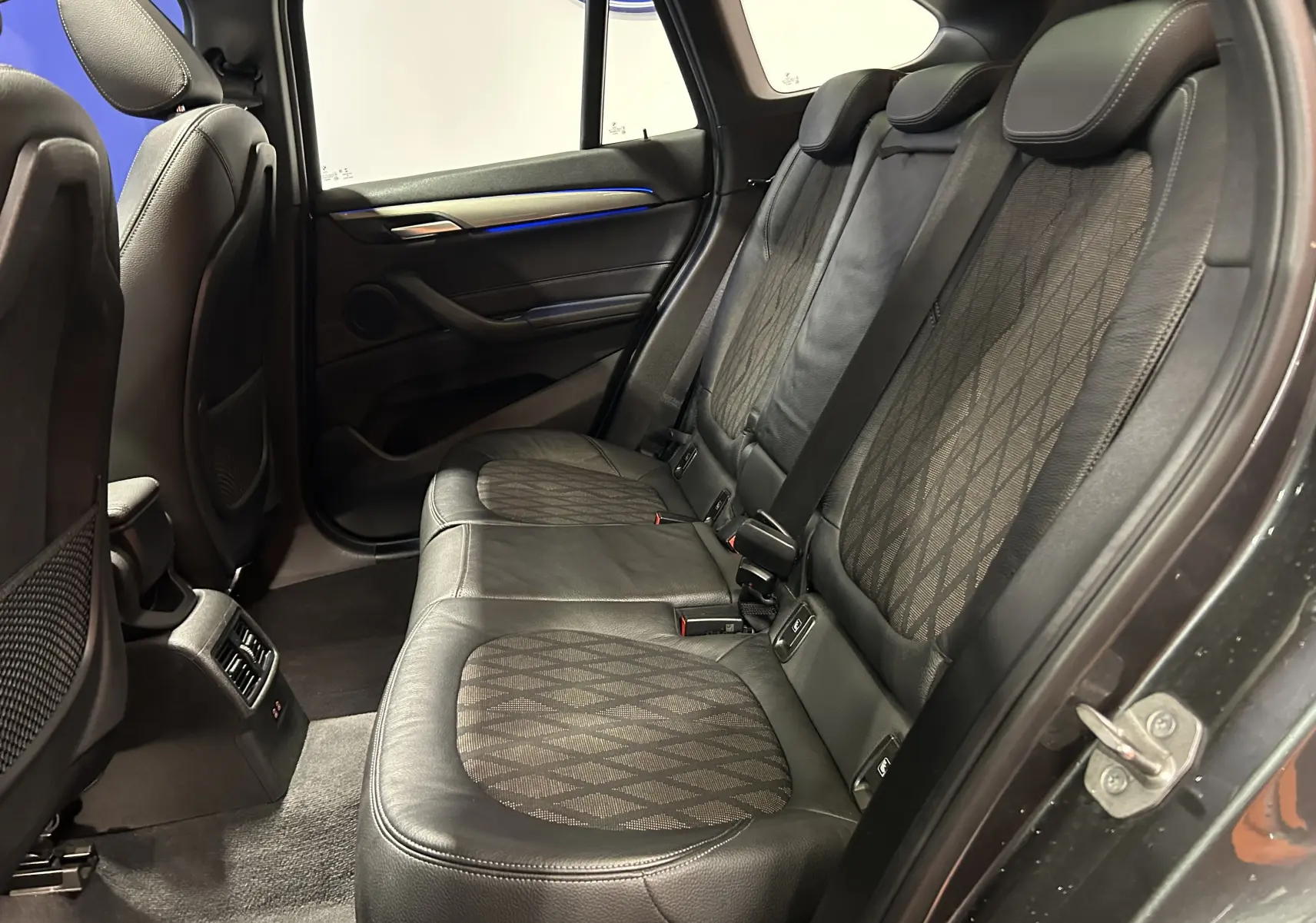 Vue intérieure côté droit des sièges arrière en cuir noir avec inserts tissu à motifs du BMW X1 gris de 2021.