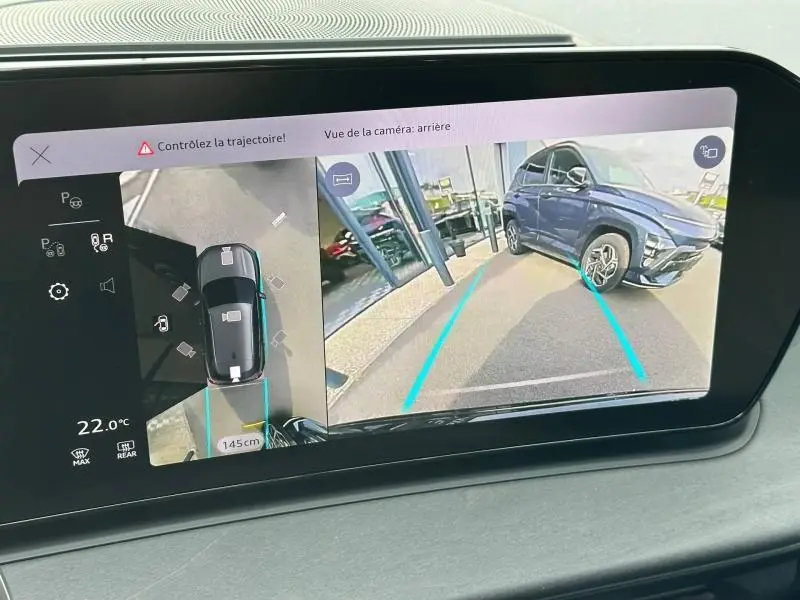 Écran tactile affichant la caméra de recul et vue 360° d’un Audi Q3 noir Mythique métallisé en stationnement.