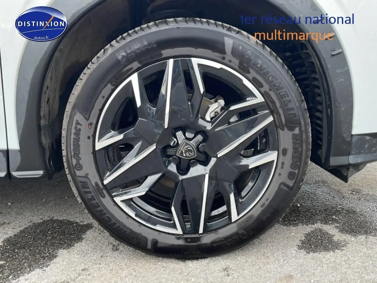 Gros plan sur la roue avant droite du Peugeot 3008 blanc, mettant en valeur la jante alu noire et argentée au design moderne.