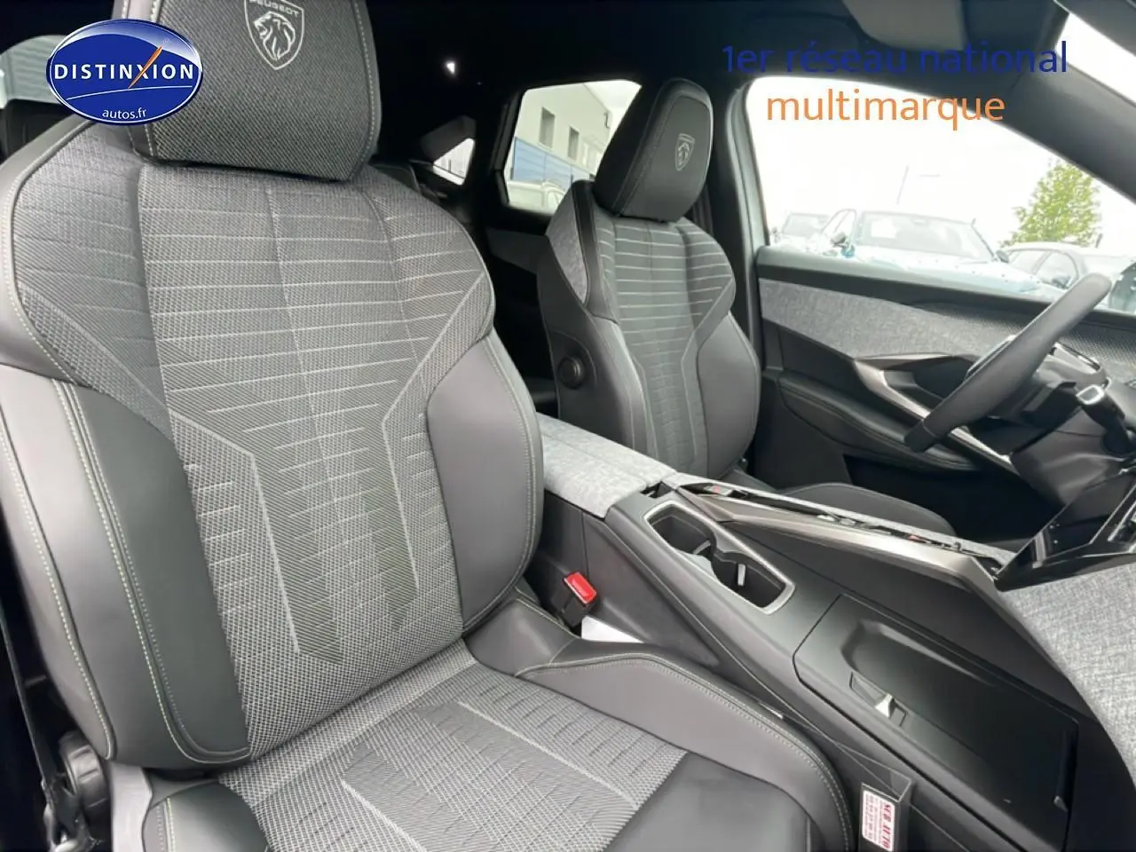 Vue intérieure du Peugeot 3008 blanc 2025, sièges avant en tissu gris et cuir avec logo Peugeot brodé.