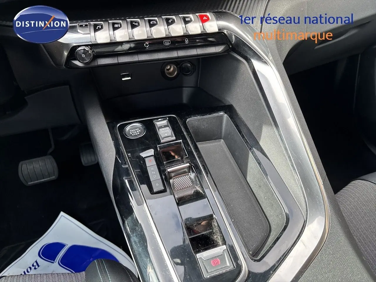 Vue rapprochée de la console centrale du Peugeot 3008 Hybrid 2024 avec commandes de boîte auto et finition noire brillante.