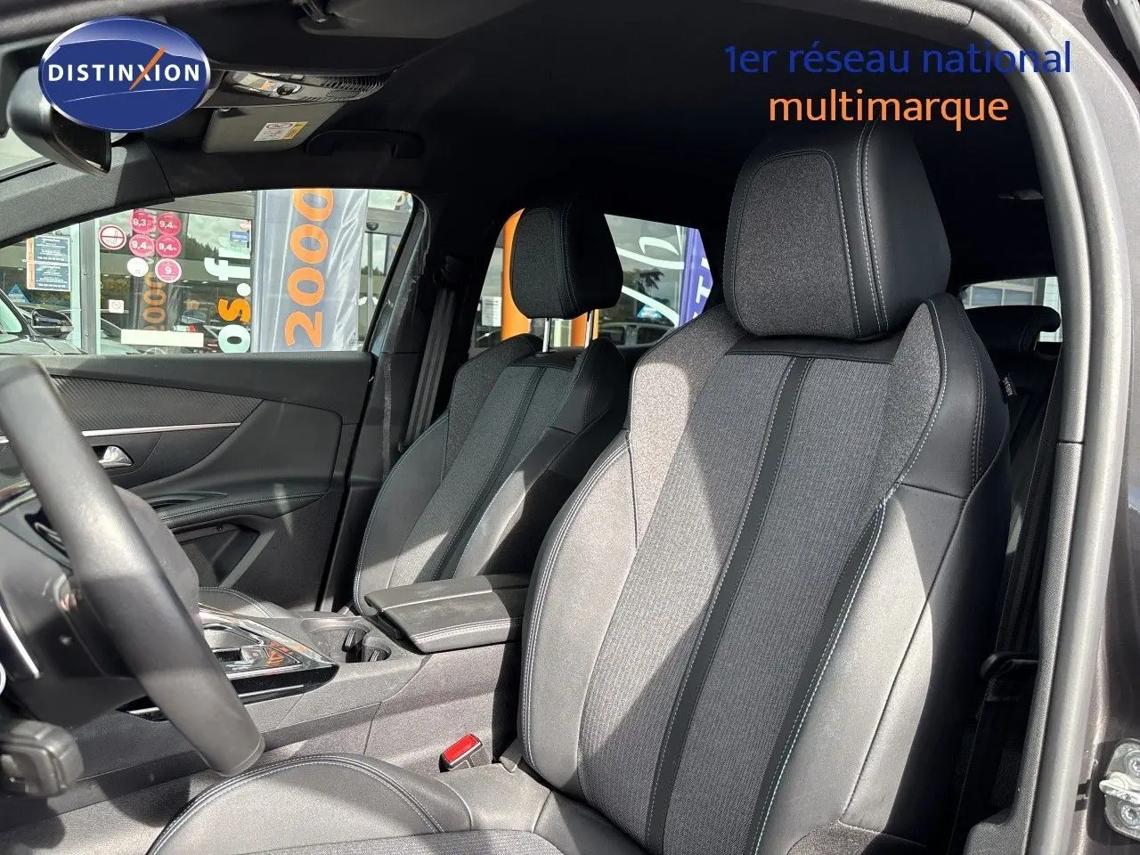 Vue intérieure côté conducteur du Peugeot 3008 HYBRID 180CH 2024, sièges tissu et cuir noir avec surpiqûres contrastées.