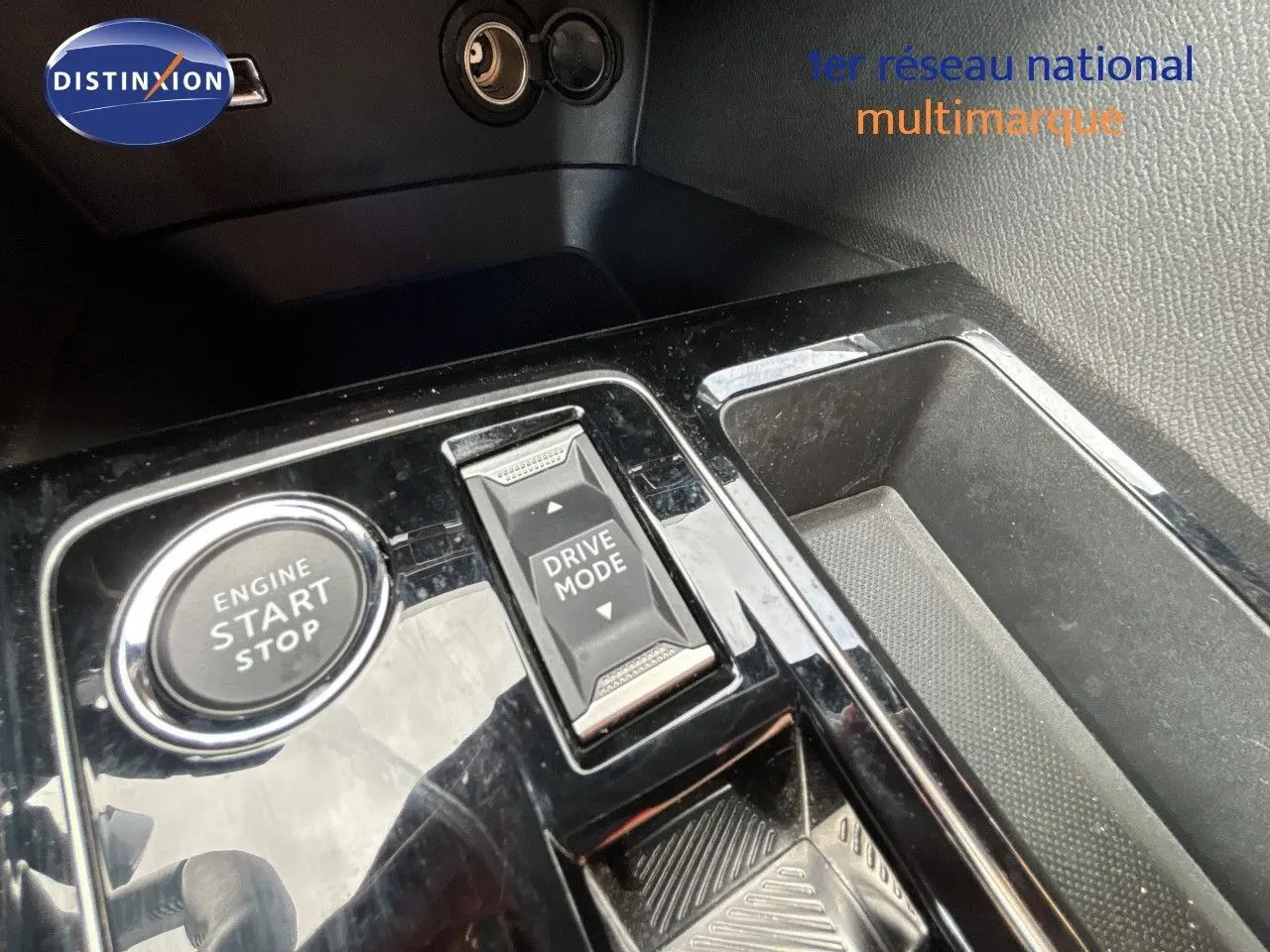 Gros plan sur la console centrale noire brillante du Peugeot 3008 Hybrid 2024 avec bouton start/stop et sélecteur drive mode.