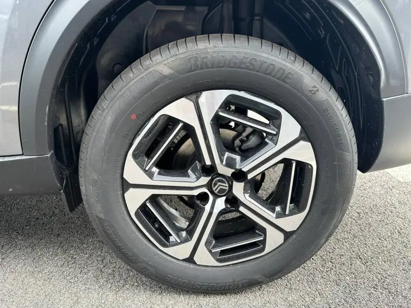 Gros plan sur la roue avant gauche du Citroën C3 Aircross gris Mercury avec jante alu bicolore distinctive.