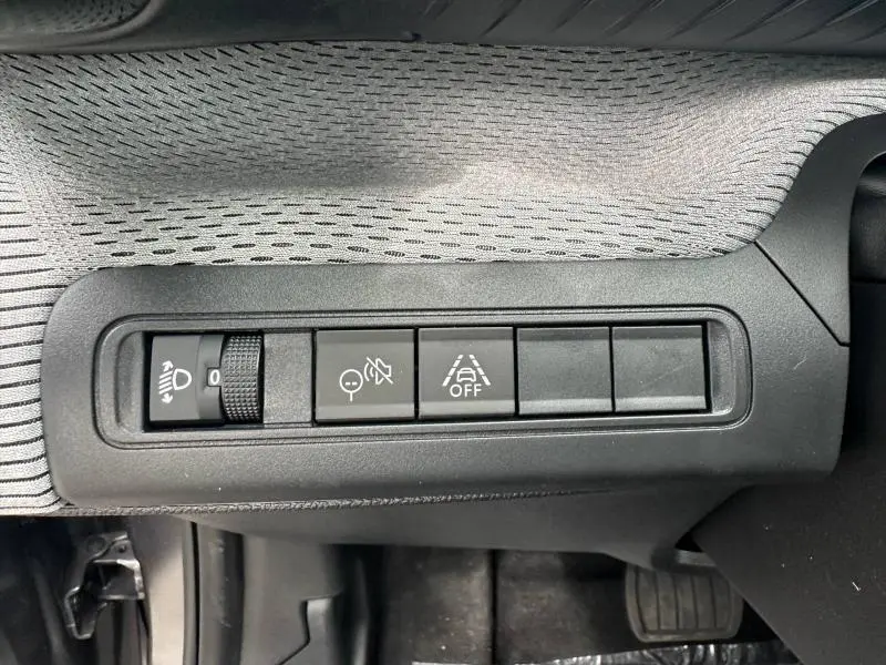 Vue rapprochée des commandes de réglage des phares et d'aide à la conduite sur la planche de bord intérieure du Citroën C3 Aircross gris Mercury.