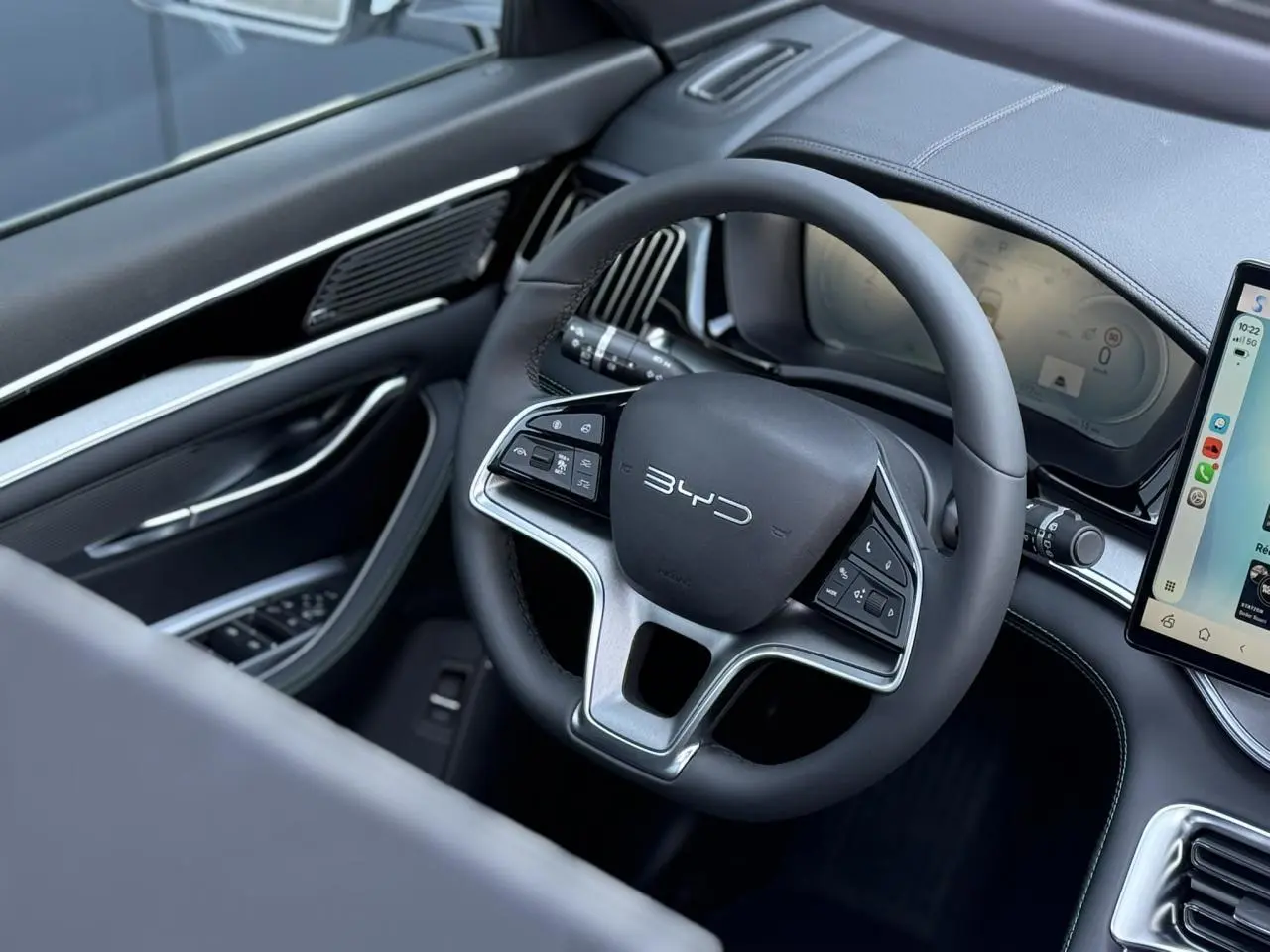 Vue intérieure côté conducteur du volant noir multifonction BYD SEAL U avec tableau de bord digital et écran tactile.
