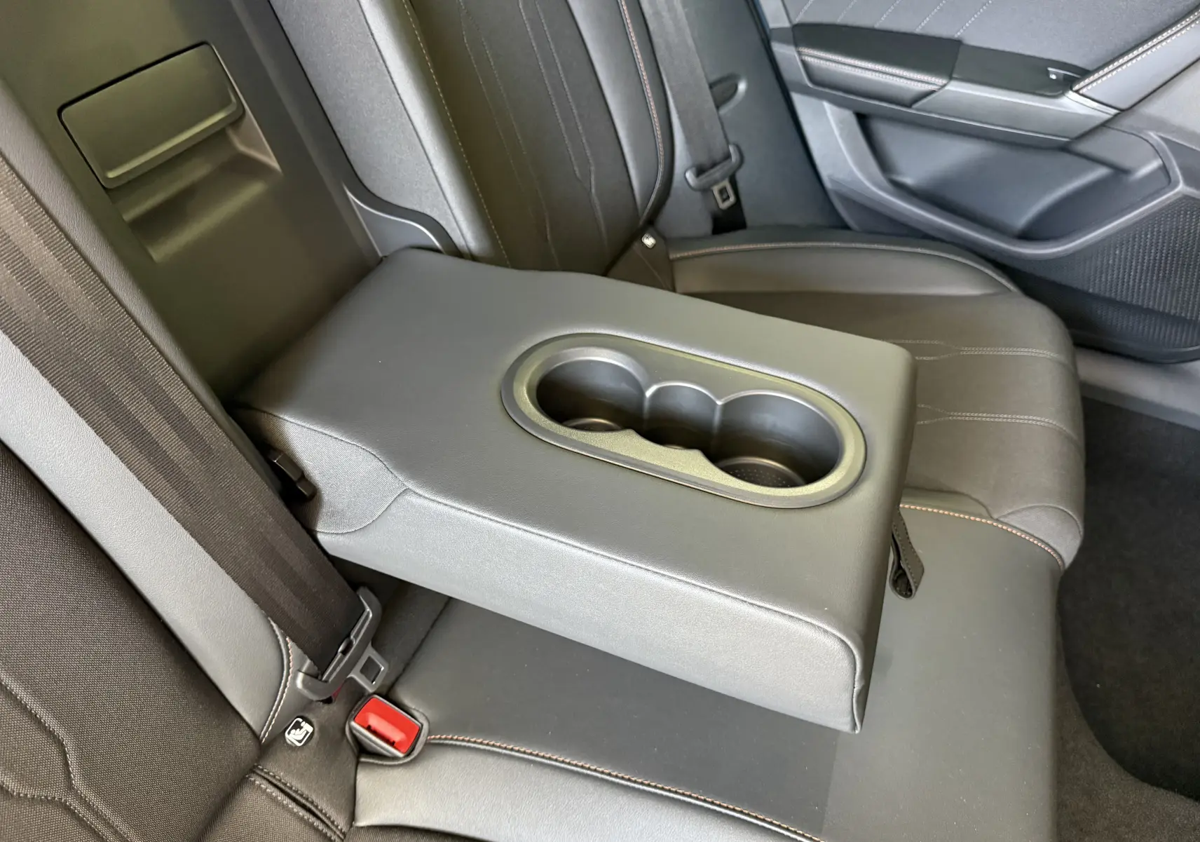 Détail de l'accoudoir central arrière avec porte-gobelets dans l'habitacle gris foncé du CUPRA Formentor 2026.
