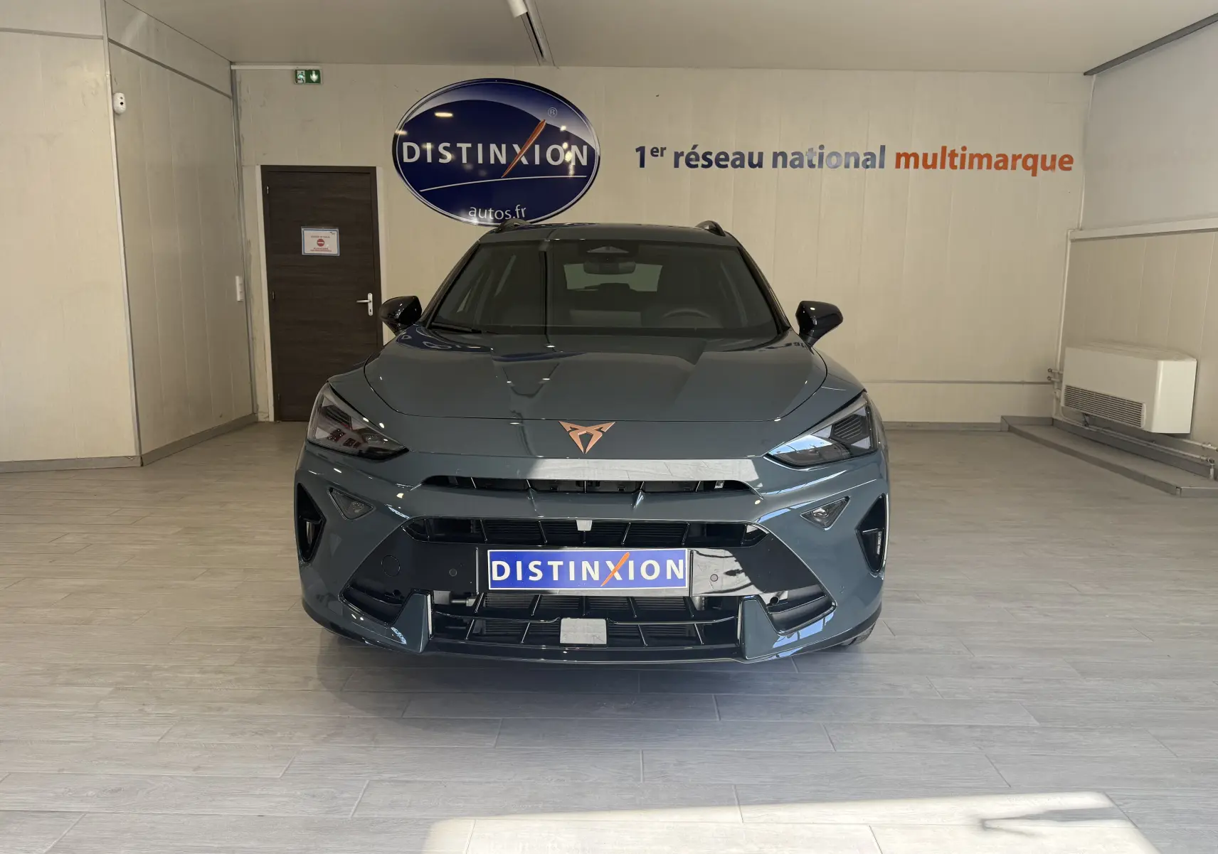 Vue frontale d'un CUPRA Formentor gris 2026 avec logo cuivré et calandre large dans un showroom.