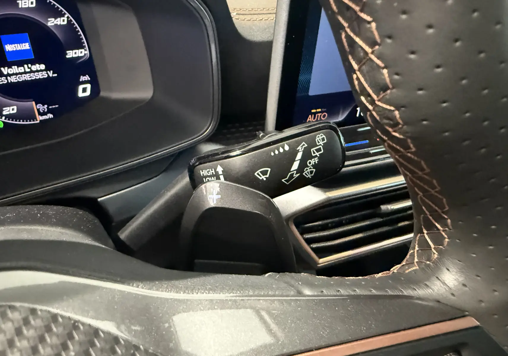 Gros plan intérieur sur le commodo de lève-glace et volant perforé avec surpiqûres marron du Cupra Formentor gris 2026.