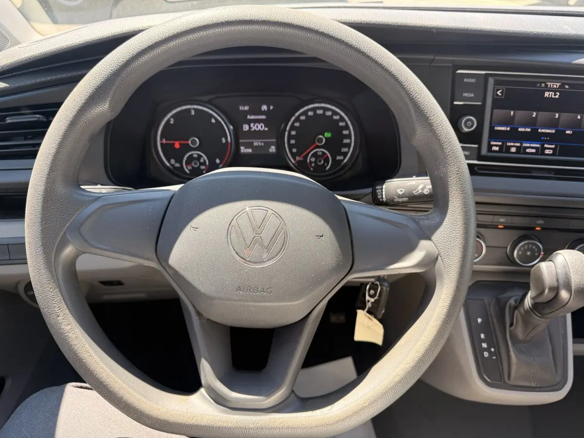 Vue intérieure centrée sur le volant Volkswagen du Transporter 2023 avec tableau de bord et écran tactile visibles.