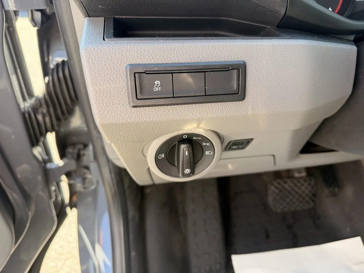 Vue rapprochée du tableau de bord côté gauche du Volkswagen Transporter gris clair, avec commande des phares et bouton antipatinage.