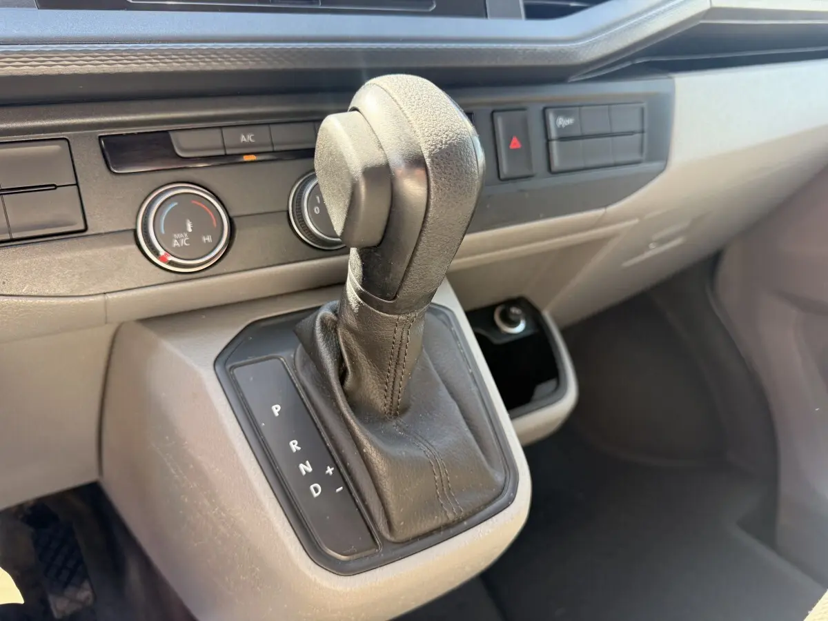 Gros plan sur la commande de boîte automatique noire dans l’habitacle gris clair du Volkswagen Transporter 2023.