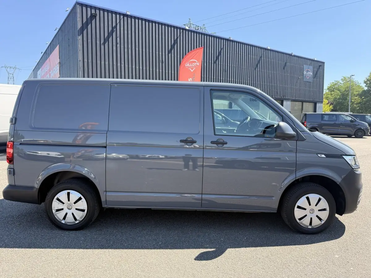 Vue latérale droite d’un Volkswagen Transporter gris clair 2023, fourgon utilitaire avec jantes acier et vitres teintées.