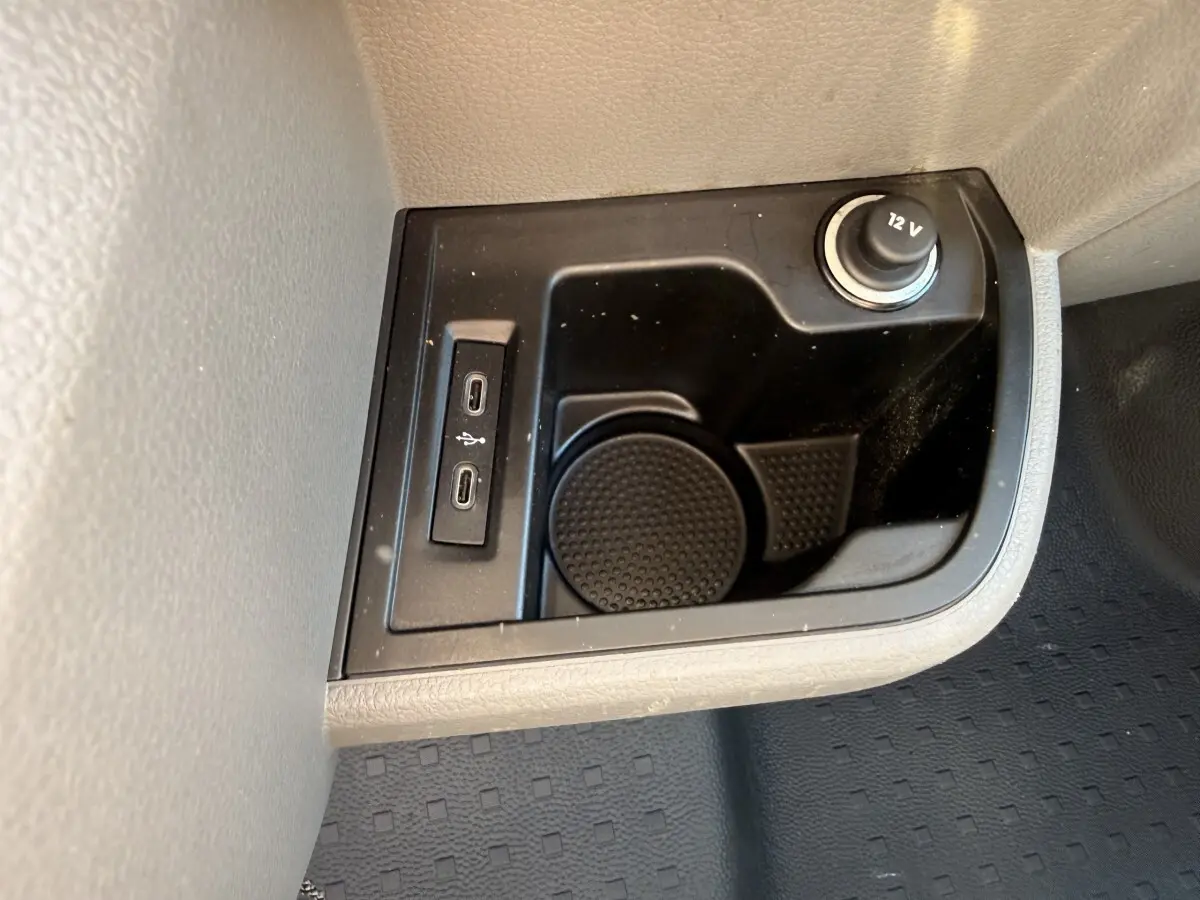 Gros plan sur la console centrale noire avec prises USB-C et prise 12V du Volkswagen Transporter gris clair 2023.