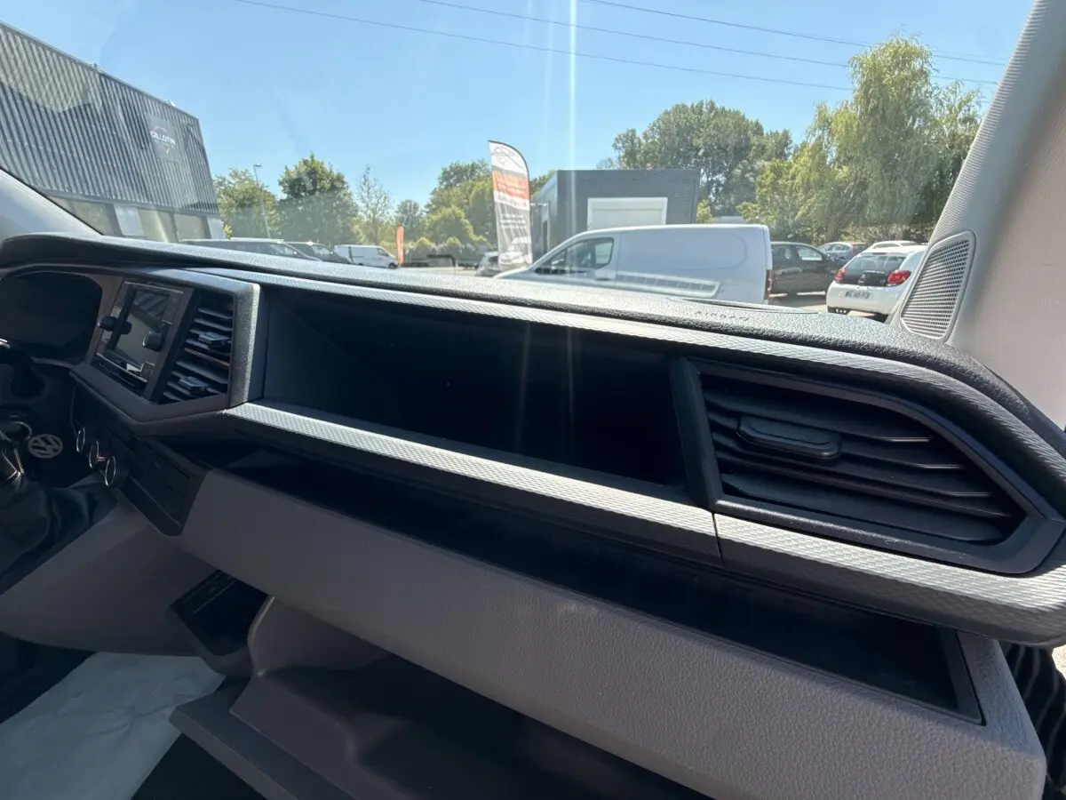 Tableau de bord gris du Volkswagen Transporter 2023 vu de l’intérieur côté passager avec écran tactile et aérateurs.