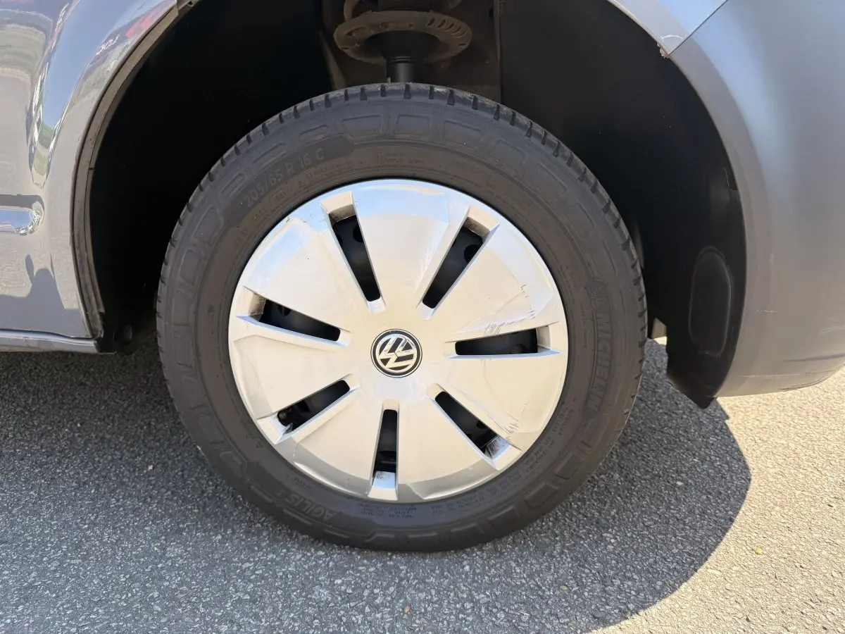 Gros plan sur la roue avant droite grise d’un Volkswagen Transporter 2023 avec enjoliveur blanc marqué VW.