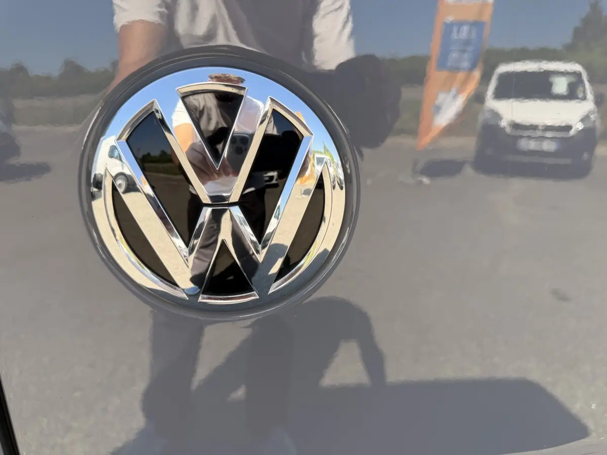 Gros plan sur le logo chromé Volkswagen sur la porte arrière d’un Volkswagen Transporter gris clair 2023.