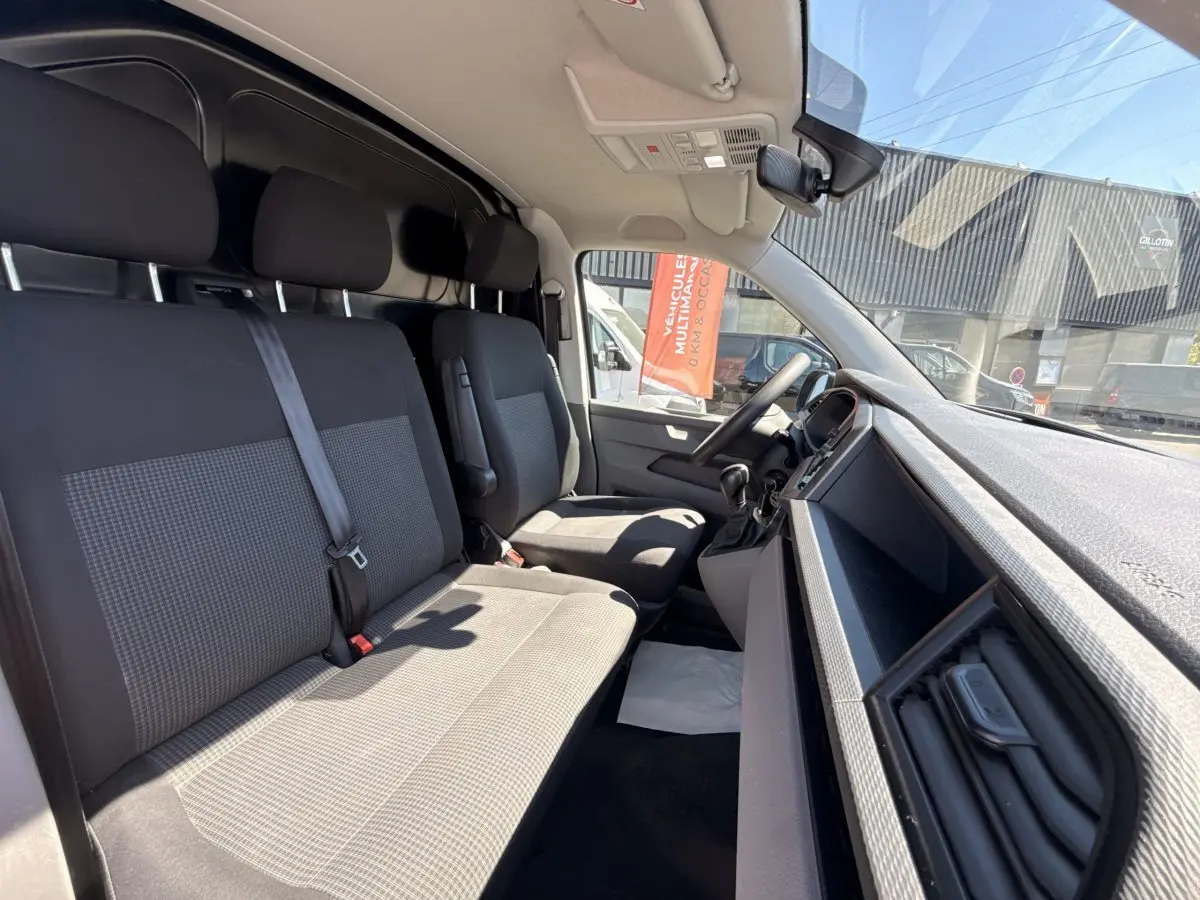 Vue intérieure côté conducteur du Volkswagen Transporter 2023, sièges tissu gris et tableau de bord noir.
