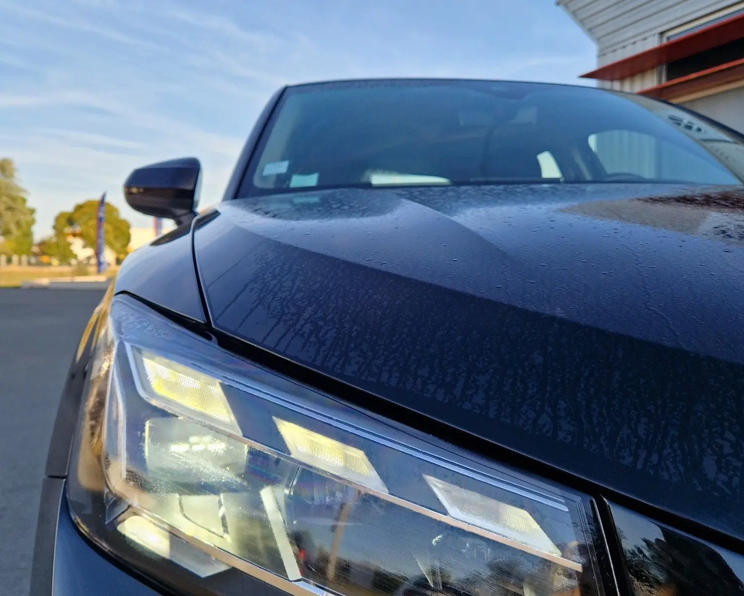 Gros plan sur le phare avant gauche d’un Audi Q2 noir 2021, mettant en valeur les LED et la carrosserie brillante.