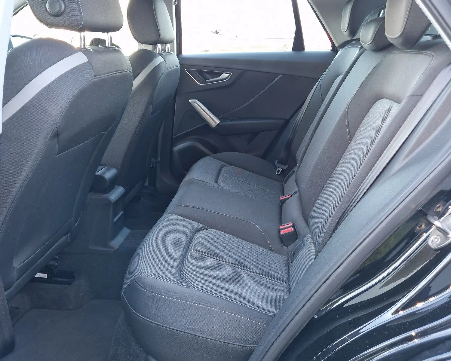 Vue intérieure côté droit des sièges arrière noirs de l'Audi Q2 35 TFSI 2021, avec habillage tissu et ceintures visibles.