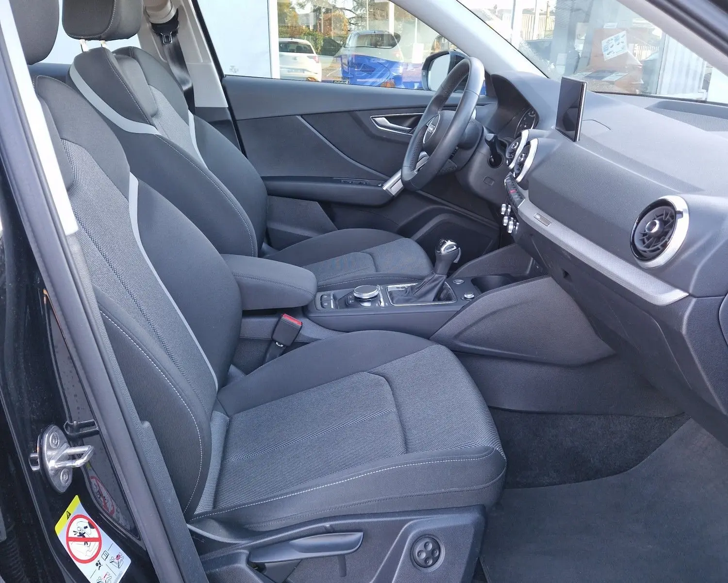 Intérieur noir de l'Audi Q2 35 TFSI 2021 vu côté conducteur, avec sièges sport et tableau de bord moderne.