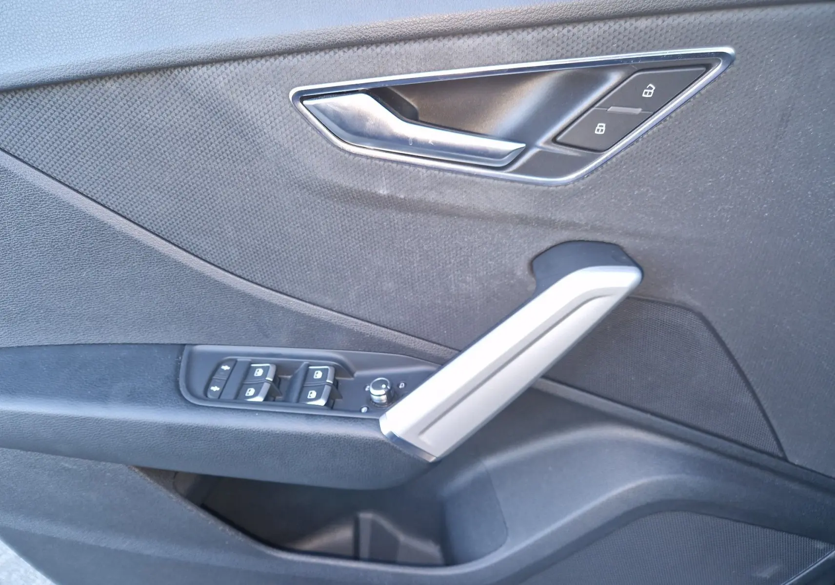 Intérieur côté gauche de la porte noire d’un Audi Q2 35 TFSI 2021, avec poignée argentée et commandes de vitres.