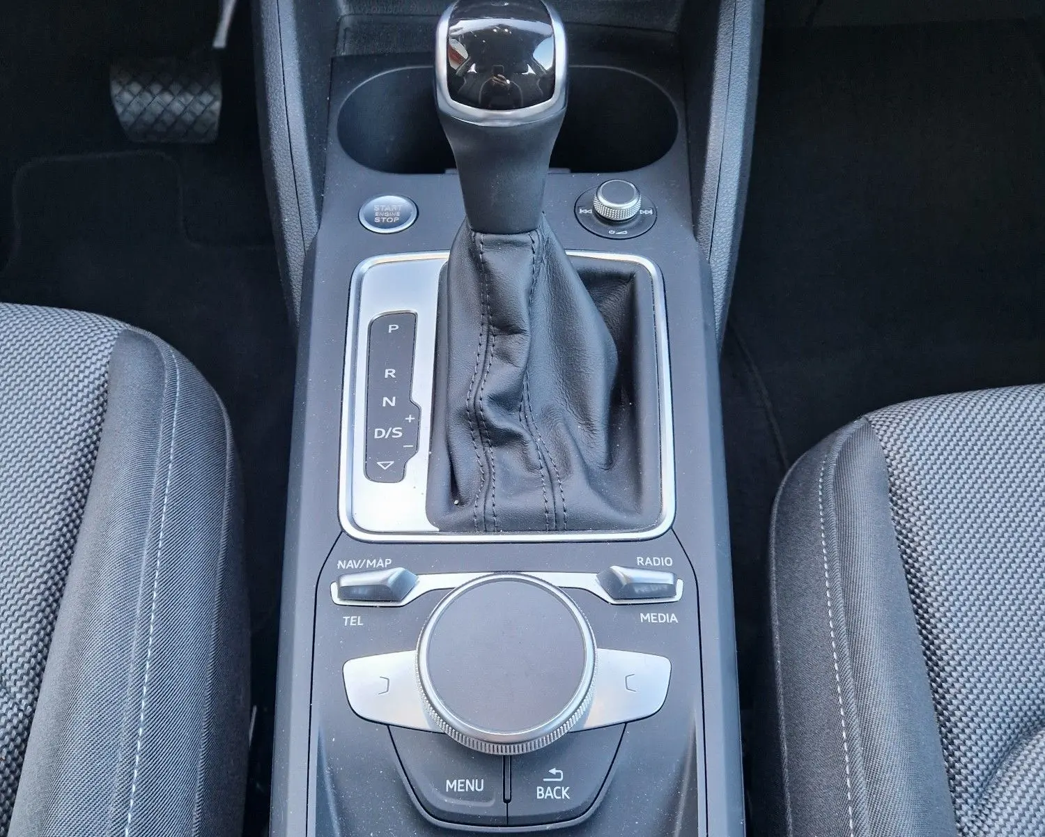 Vue plongeante sur la console centrale noire de l’Audi Q2 35 TFSI 2021, avec levier de vitesse automatique et commandes multimédia.
