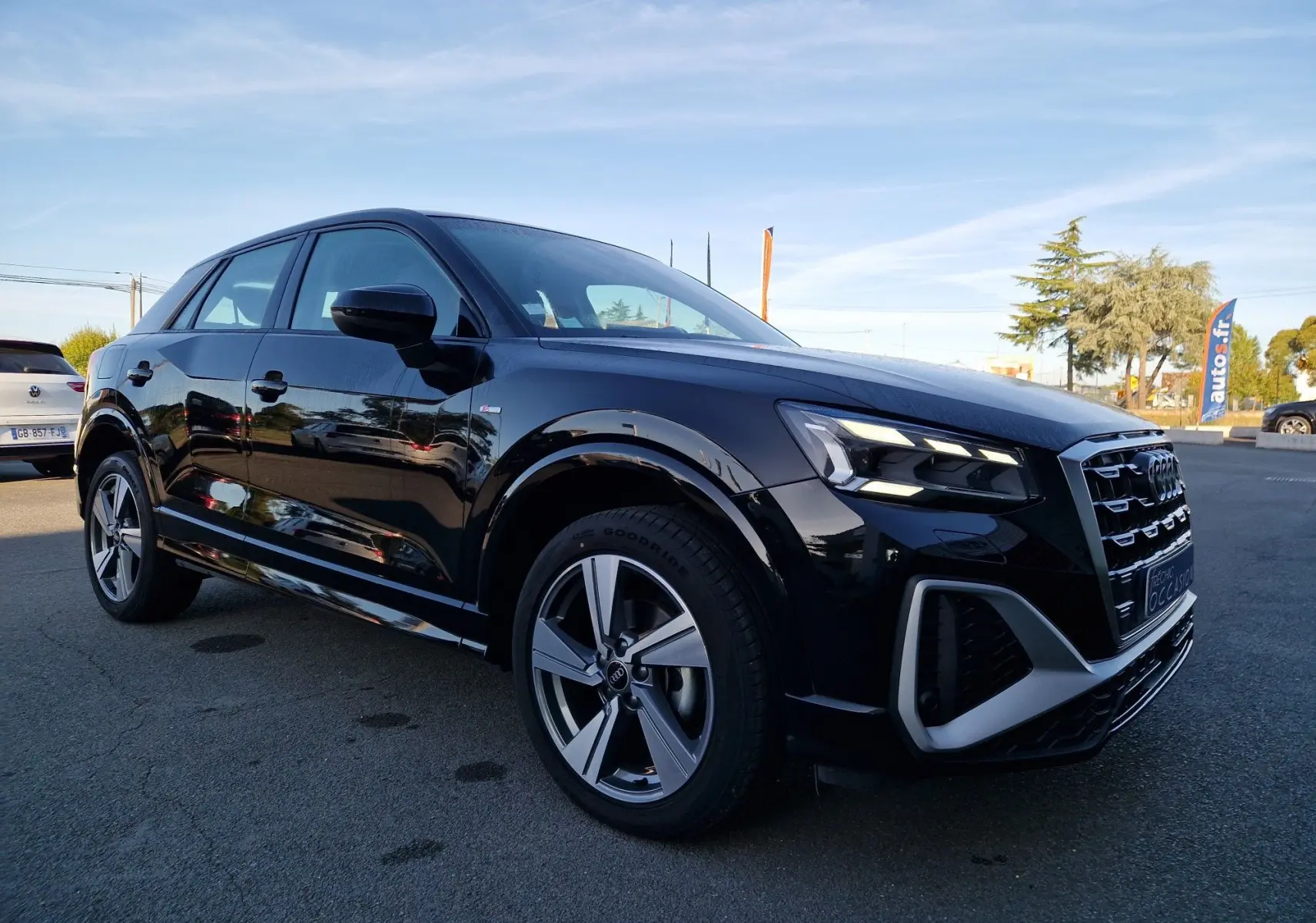 Audi Q2 noir en vue 3/4 avant droit, avec phares LED allumés et jantes alliage distinctives.