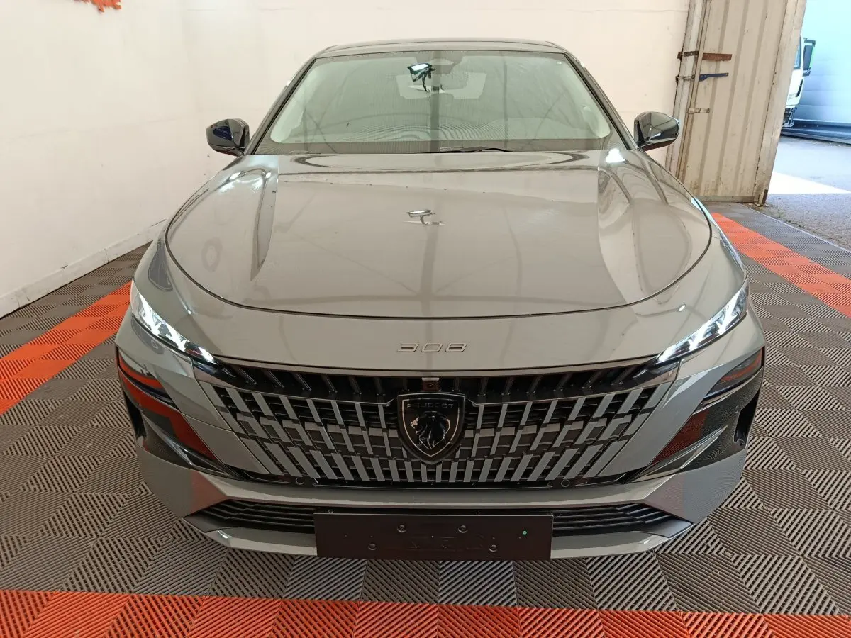 Vue avant frontale d'une Peugeot 308 gris foncé avec calandre distinctive et phares LED fins.