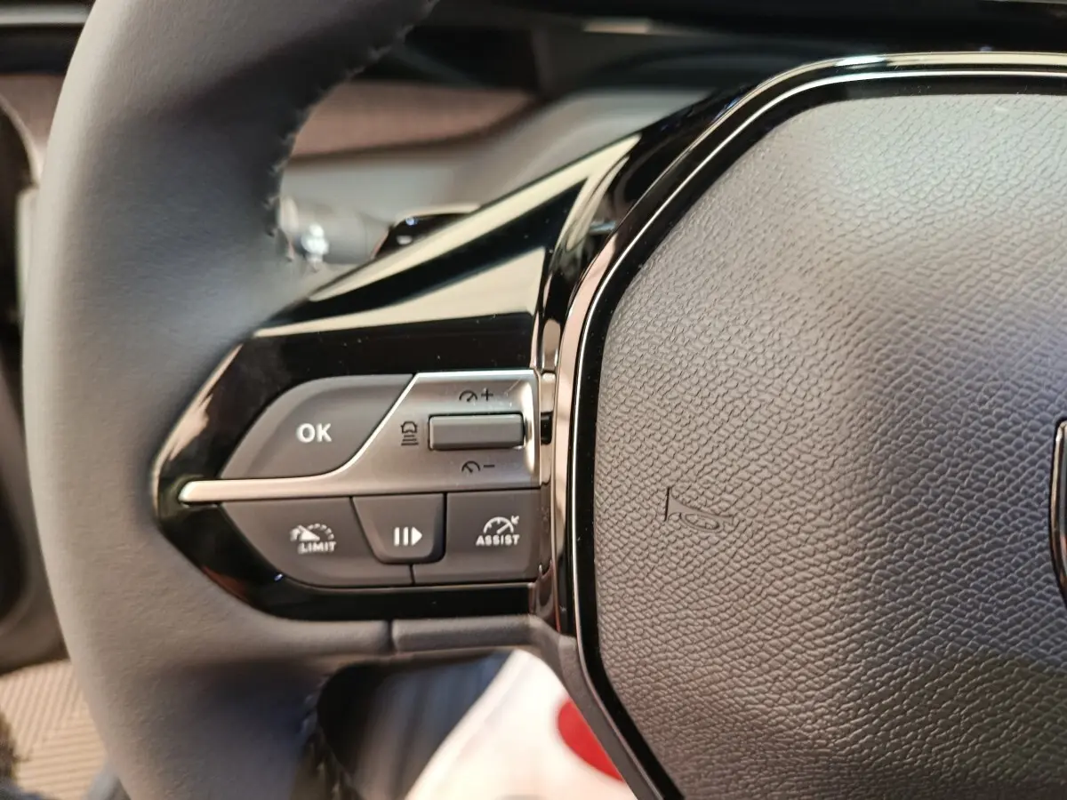 Gros plan sur le volant cuir multifonctions gris foncé de la Peugeot 308 BlueHDi 130 CH EAT8 Allure, côté gauche.