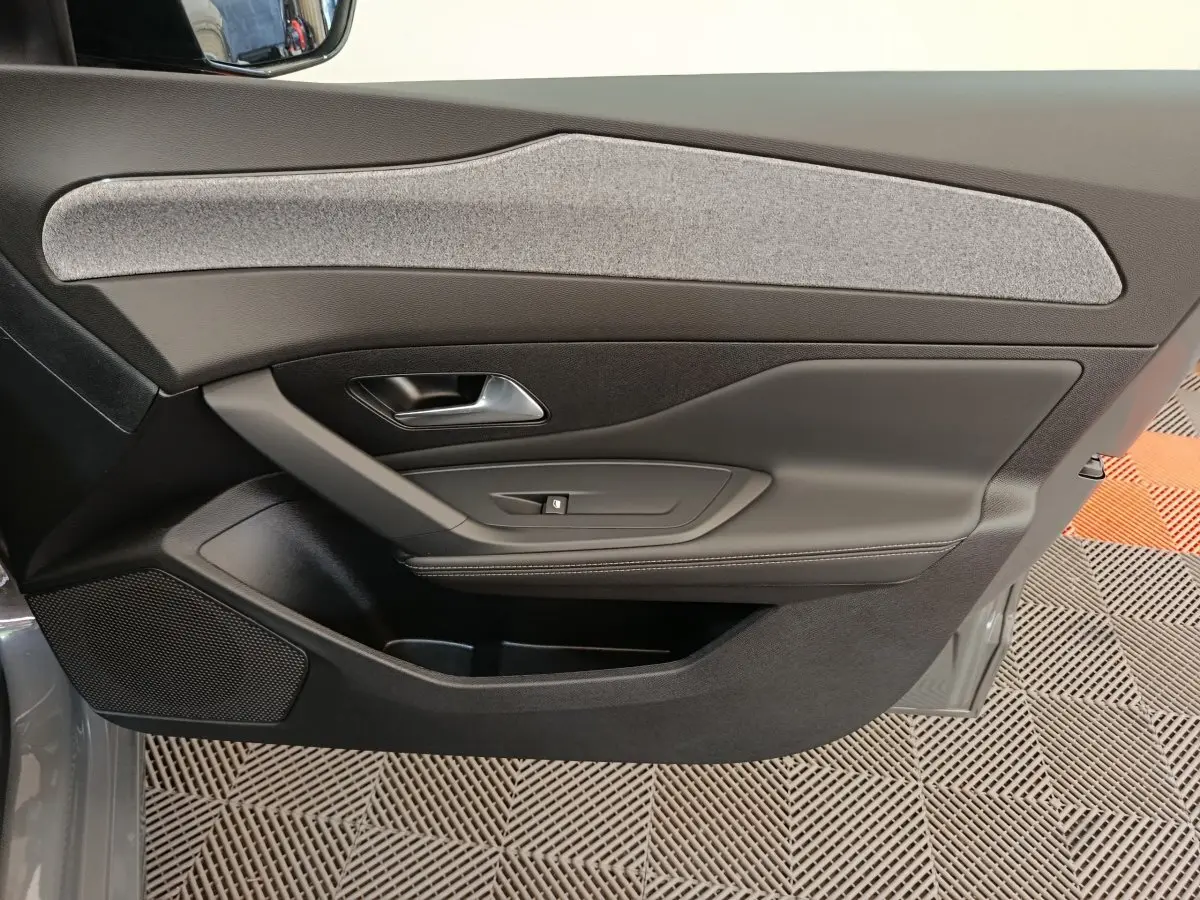 Vue intérieure côté gauche de la porte arrière gris foncé de la Peugeot 308 2026 avec insert tissu clair et poignée métal.