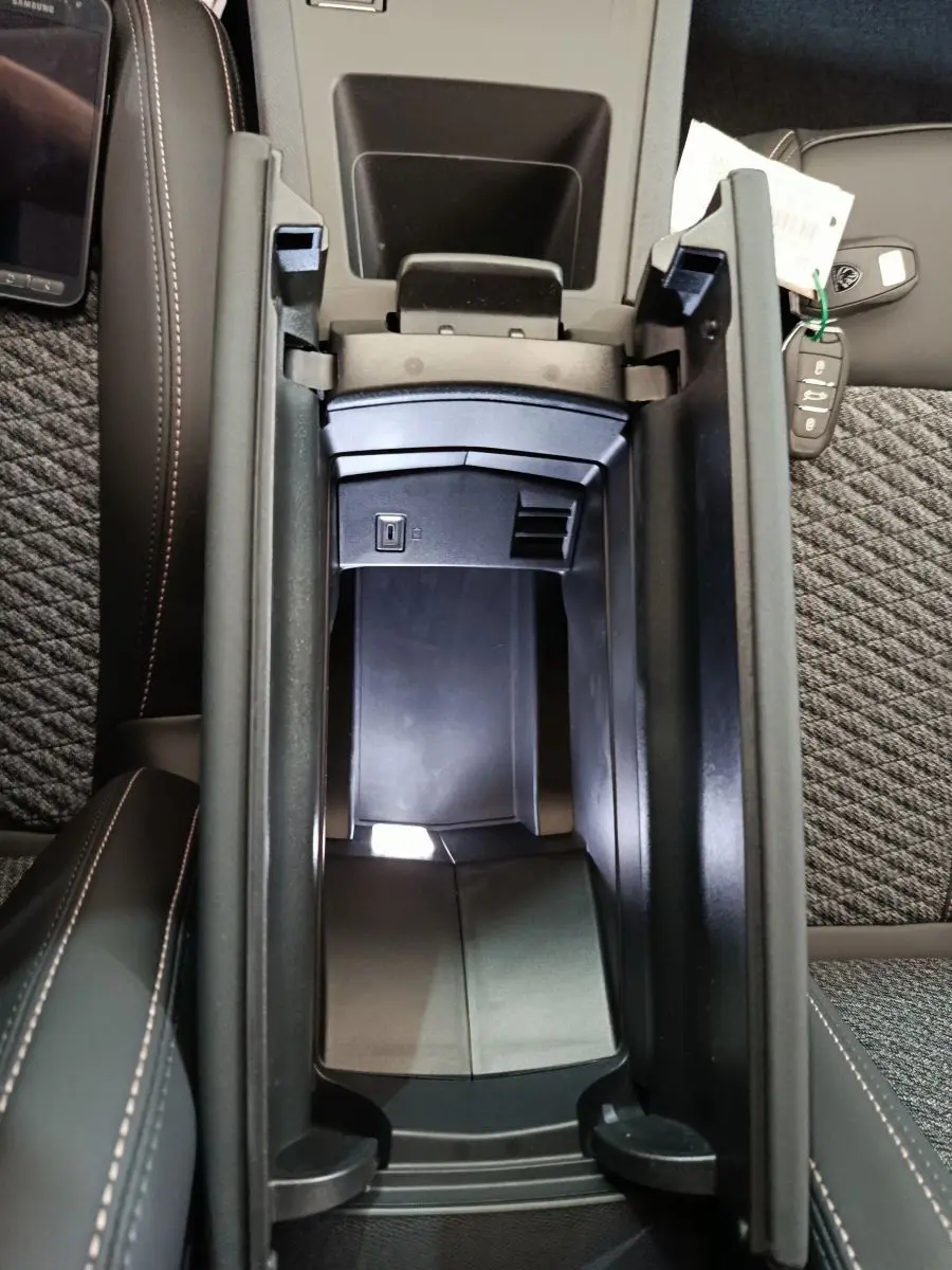 Vue plongeante sur l'accoudoir central ouvert de la Peugeot 308 gris foncé, avec clé et port USB visibles.